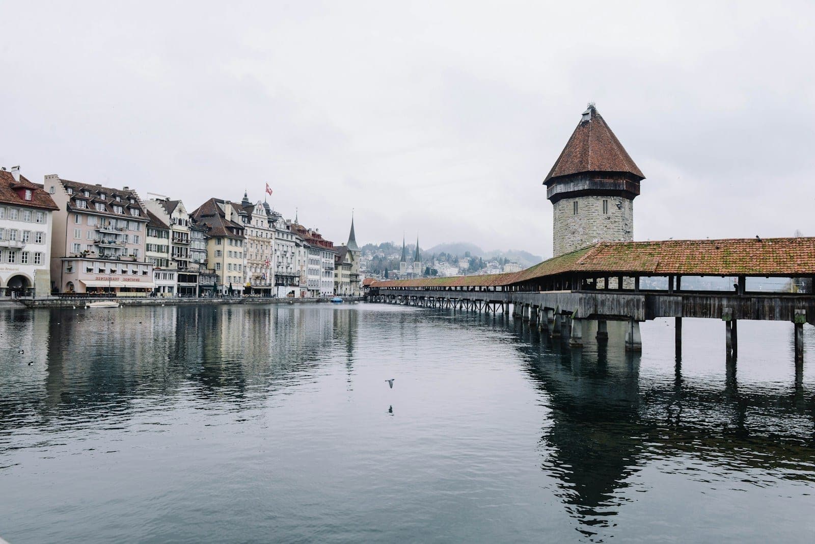 Covered wooden bridge crossing a river in front of an old town
